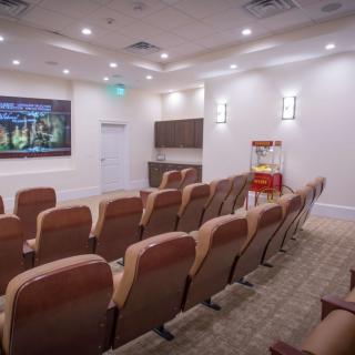 A modern theater room with comfortable seating and a large screen.