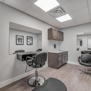 A modern hair salon interior with chairs, mirrors, and cabinets.