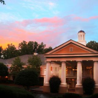 A classic building with prominent columns stands against a colorful sunset sky.