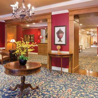 Elegant hotel lobby featuring a chandelier, wood paneling, and a table with flowers.