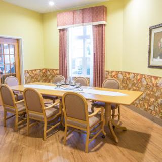 A spacious conference room featuring a wooden table and comfortable chairs, illuminated by natural light.