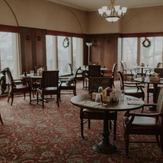 A cozy dining room with elegantly set tables and large windows.