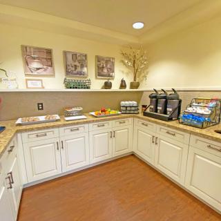 A well-organized kitchenette featuring a coffee station with beverage dispensers, snacks, and ample countertop space.