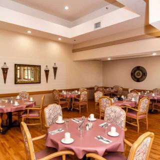 An empty restaurant dining room with neatly arranged tables and chairs, ready for guests.