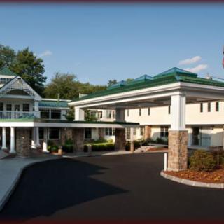The image shows the entrance of a hotel with a covered driveway and modern architectural design.