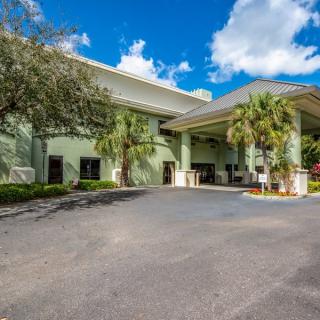 A hotel entrance with palm trees and a clear blue sky.