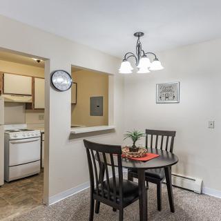 A cozy dining area with a small round table and two chairs, adjacent to a compact kitchen.