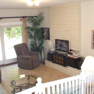 A cozy living room featuring a recliner, television, and coffee table next to a brick accent wall and sliding glass door.