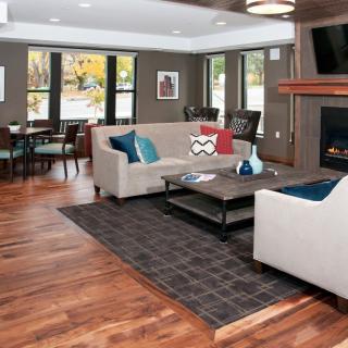 A modern living room featuring comfortable seating around a central coffee table, with a cozy fireplace and elegant wood flooring.
