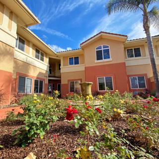 A beautiful residential building surrounded by a vibrant garden of flowers under a clear blue sky.