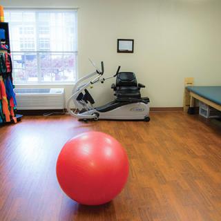 A physical therapy room with a stationary bike and an exercise ball.