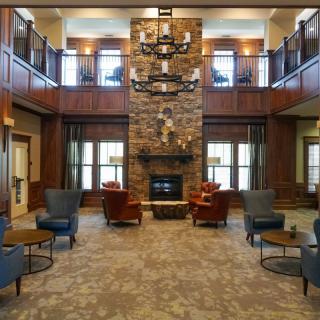 A cozy lobby with a central stone fireplace and comfortable seating.