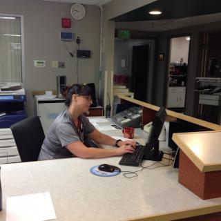 A staff member working at a reception desk in an office environment.