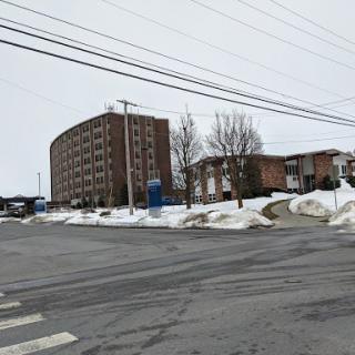 A view of a snowy urban area featuring a multi-story building and residential units.