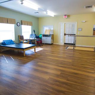 A therapy room with exercise equipment and wooden flooring.