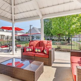 A cozy outdoor seating area under a gazebo with red cushioned furniture by the pool.