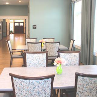 A spacious dining area featuring a light blue wall, modern furniture, and a decorative floral centerpiece.