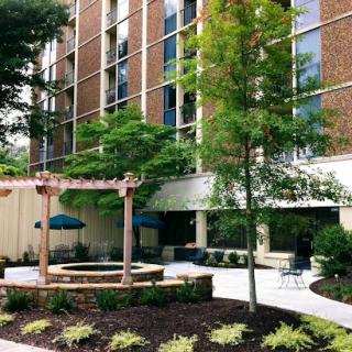 A modern building featuring a landscaped outdoor area with trees and seating.