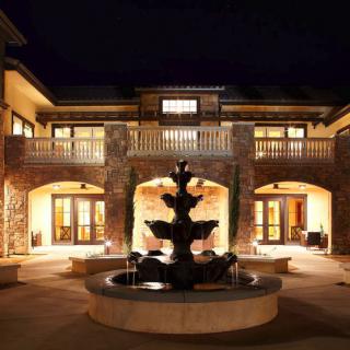 A beautifully illuminated building at night with a fountain in the courtyard.