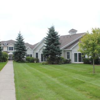 A charming residential building surrounded by well-maintained lawns and trees.