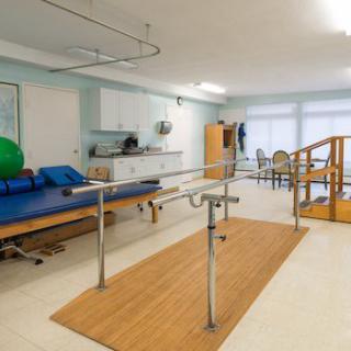 A well-equipped physical therapy room with parallel bars and other rehabilitation equipment.