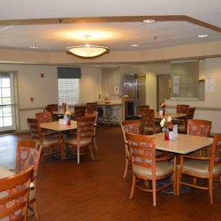 An empty dining area with neatly arranged tables and chairs, featuring warm lighting.
