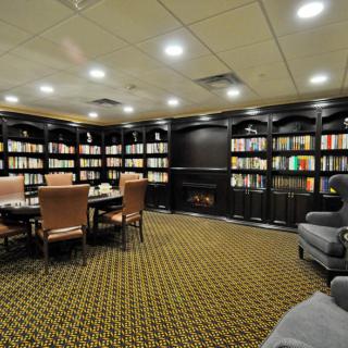 A cozy library room with bookshelves, comfortable chairs, and warm lighting.