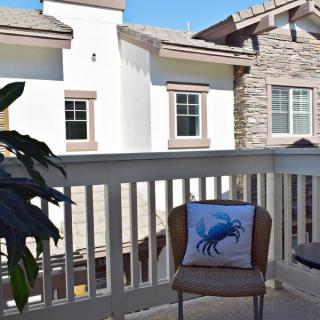 A cozy balcony with a chair featuring a crab-design cushion, overlooking neighboring houses.