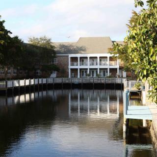 A tranquil view of a building with its reflection in the water, surrounded by trees.