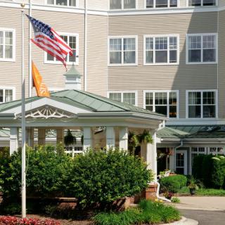 A residential building with an entrance, featuring greenery and flags.