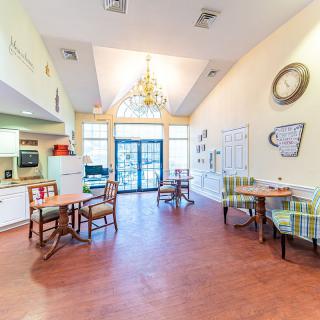 A cozy kitchen and dining area with a chandelier, tables, and chairs.