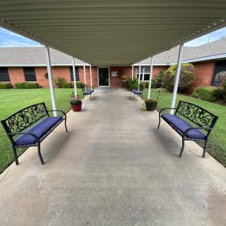 A serene outdoor pathway lined with benches, leading to a welcoming building.