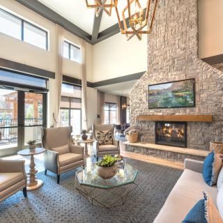 A luxurious living room with a high ceiling, stone fireplace, and modern decor.