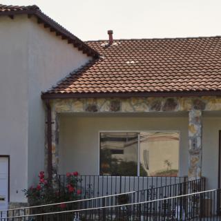 A house with a tiled roof, stone accents, and a small patio area.