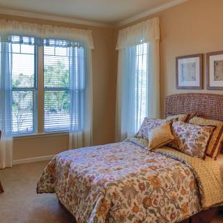 A cozy bedroom with a large window, featuring elegant decor and comfortable furnishings.