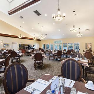 A spacious restaurant dining area with elegantly set tables and chandeliers.