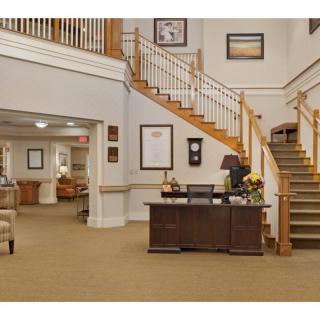A spacious lobby with a central reception desk and a grand staircase.