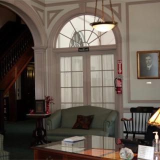 A cozy lobby area with traditional furniture and a portrait on the wall.
