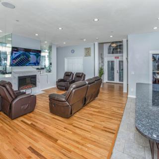 A modern living room featuring hardwood floors, comfortable recliners, a fireplace, and a large television.