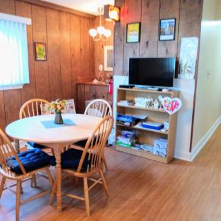 A cozy dining room with wood paneling, featuring a round dining table with chairs and a small entertainment area.