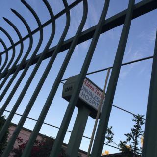 A secure fenced area with a warning sign against a clear blue sky.