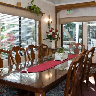 A well-furnished dining room with a long wooden table, surrounded by chairs and decorated with a centerpiece on a red runner.