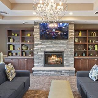 A cozy living room with a stone fireplace, surrounded by shelves and comfortable seating.
