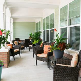 A cozy porch with wicker furniture and lush green plants.