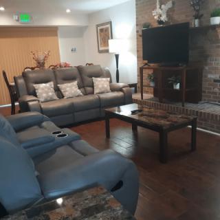 A cozy living room with comfortable seating, a coffee table, and a wall-mounted TV.