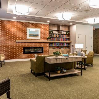 A modern and cozy living room featuring a fireplace, comfortable seating, and a bookshelf.
