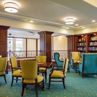 A cozy library seating area with chairs, tables, and bookshelves.