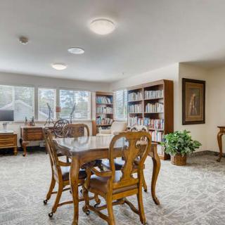 A spacious and well-lit dining area with wooden furniture and bookshelves.