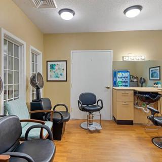 Interior view of a salon with chairs, hair dryers, and a mirror.