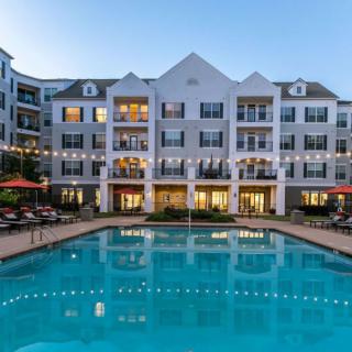 A well-lit apartment complex with a swimming pool at dusk.
